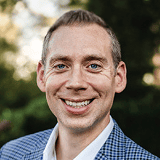 Business professional smiling outdoors, representing alignment and success.