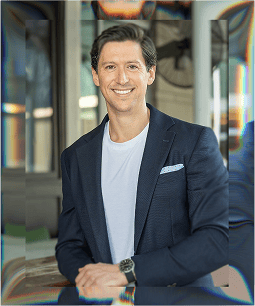 Confident businessman in formal attire smiling in modern office setting.