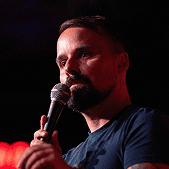 Confident speaker holding a microphone during a presentation on alignment strategies.